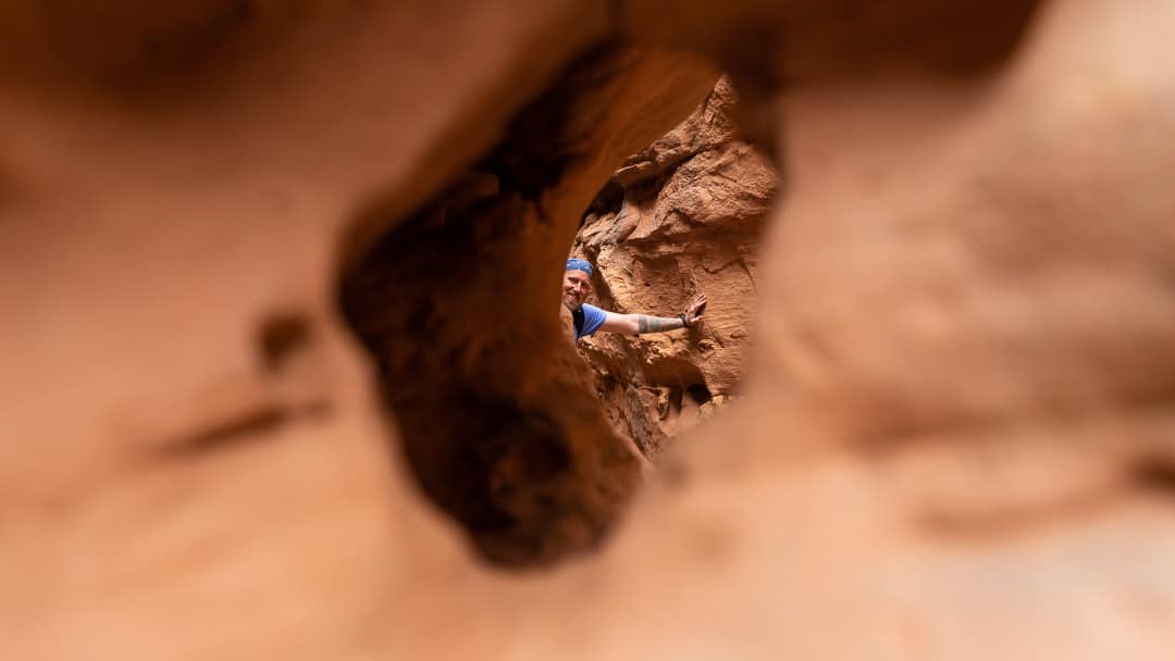 Chris peeking through a hole in a rock