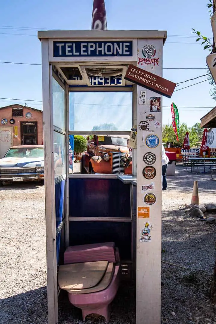 Old telephone booth with a toilet inside behind Delgadillos