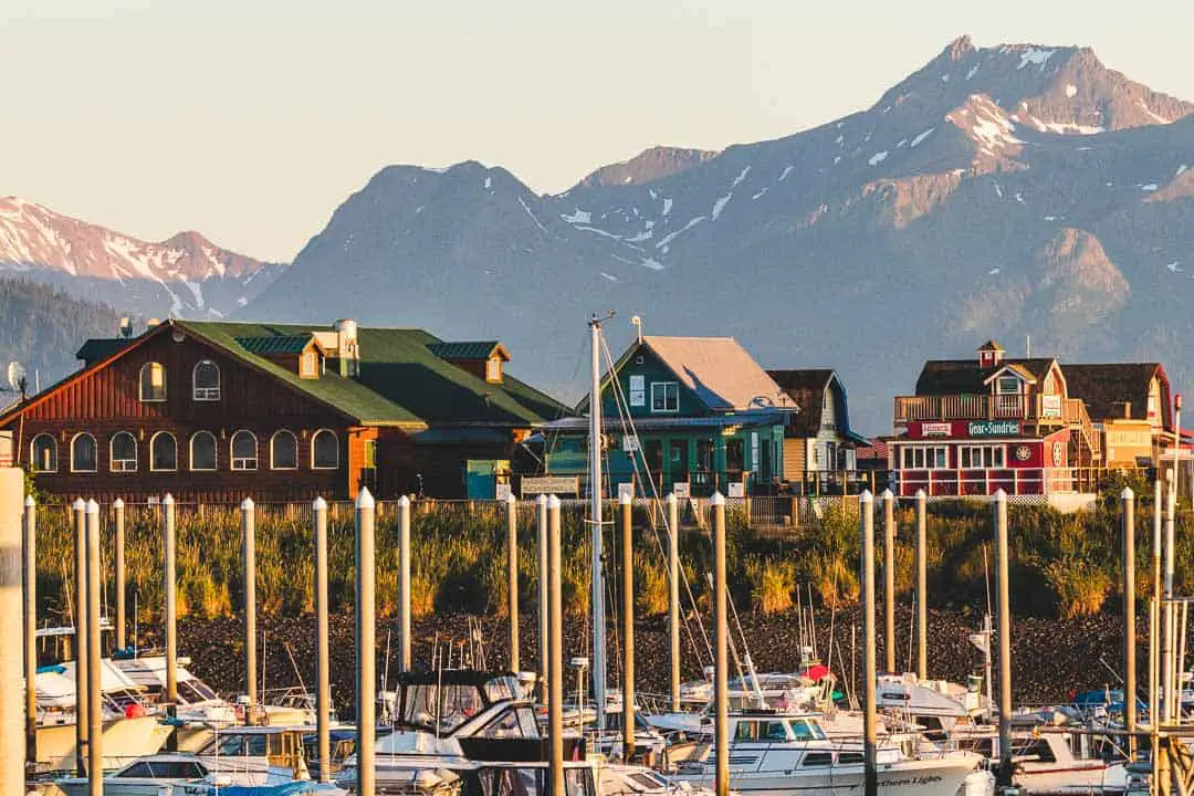 Boats in the foreground with buildings in the middle and mountains in the background