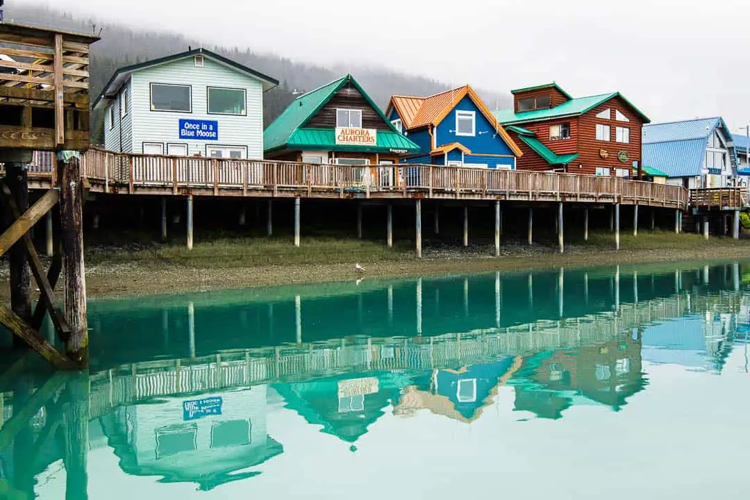 Row of buildings on a wooden deck with reflection in blue water