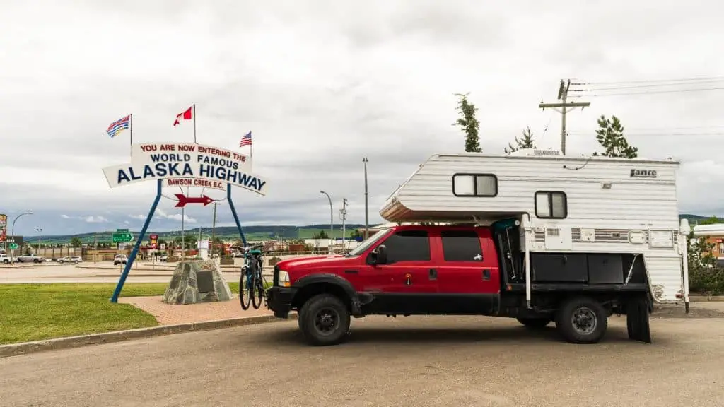 Lance Camper on a Flatbed Truck at Alaska Highway Sign