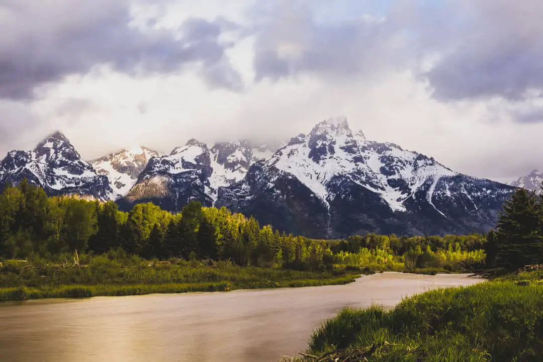 Cloudy sunrise at a river bend with scenic mountain range in the background