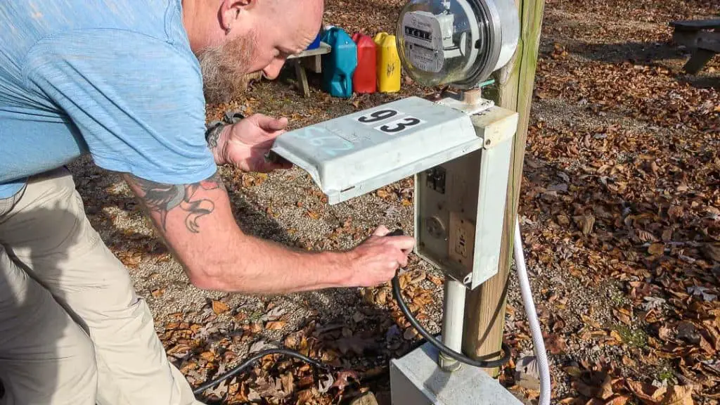 Man plugging in camper cord to electric