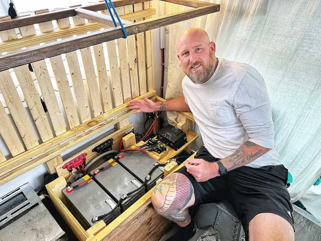 Man showing off power setup and battery bank in a RV