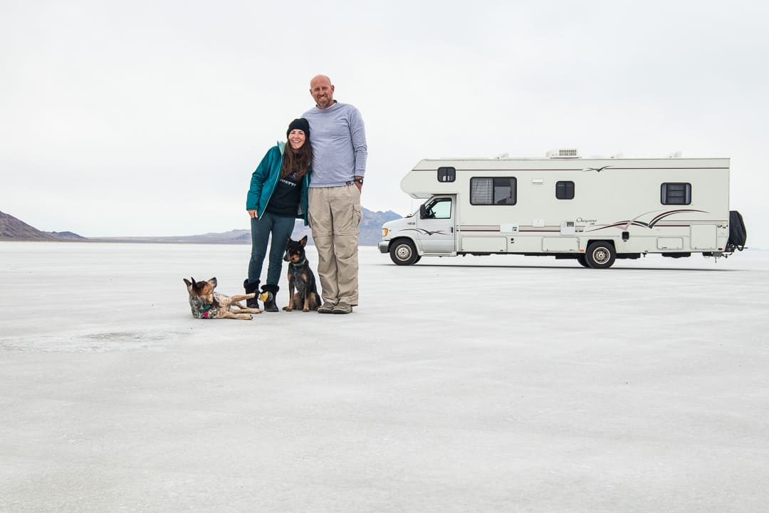 Couple posing with their dogs in front of their RV on the Bonneville Salt Flats