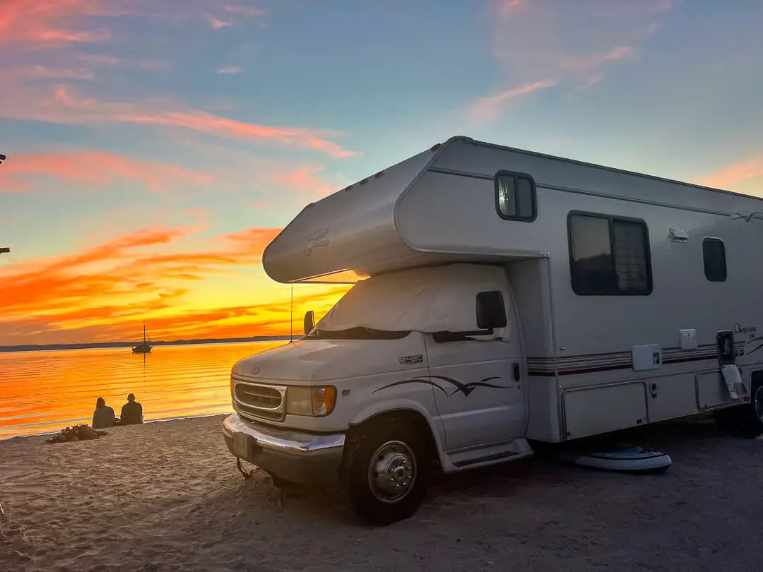 RV parked on a beach at sunset